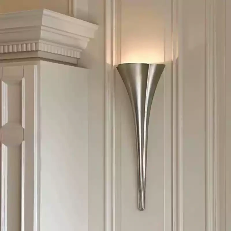 Silver tapered wall sconce installed on a paneled wall